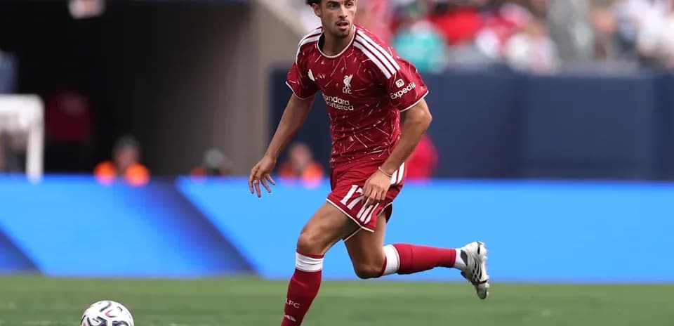 Player in red Liverpool kit dribbling ball on field