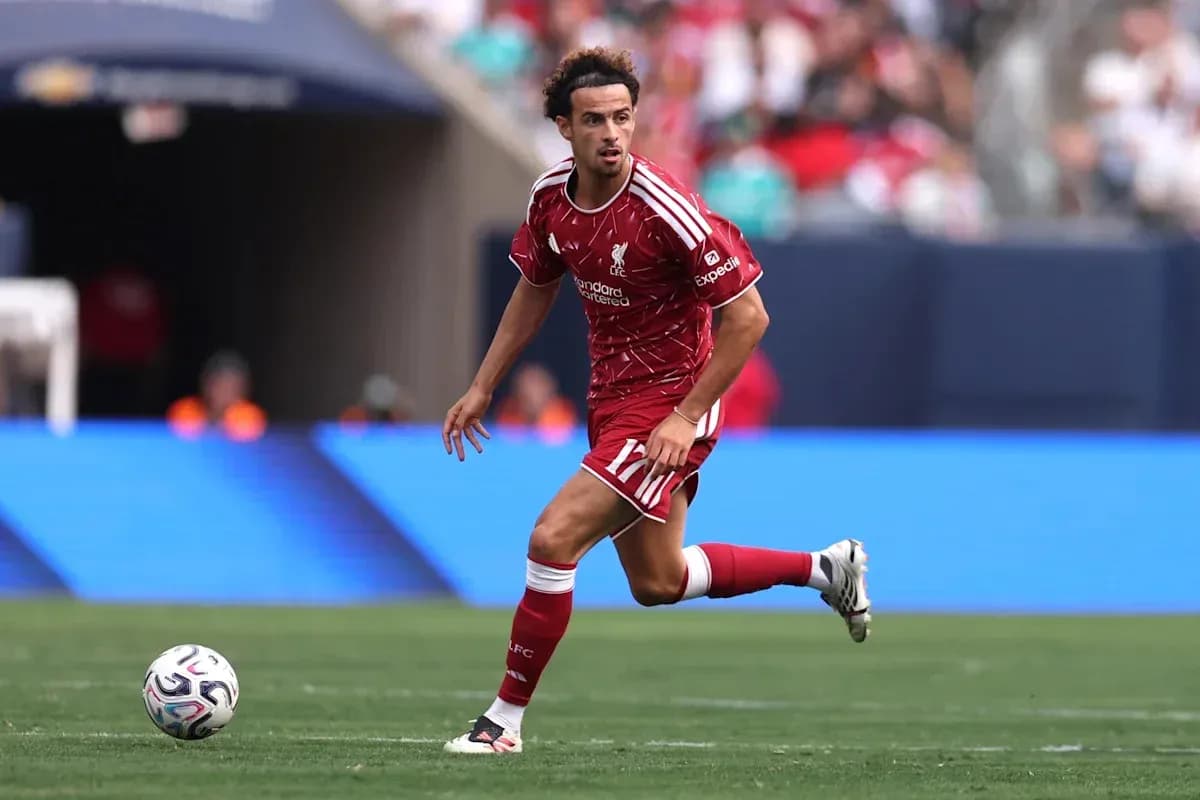 Player in red Liverpool kit dribbling ball on field