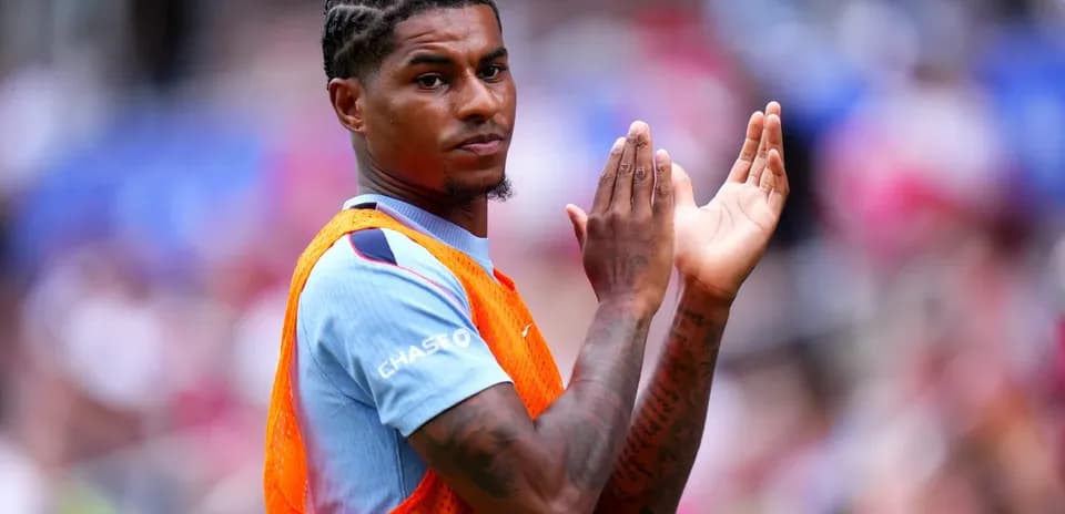 Player in warm-up jersey clapping on the sidelines