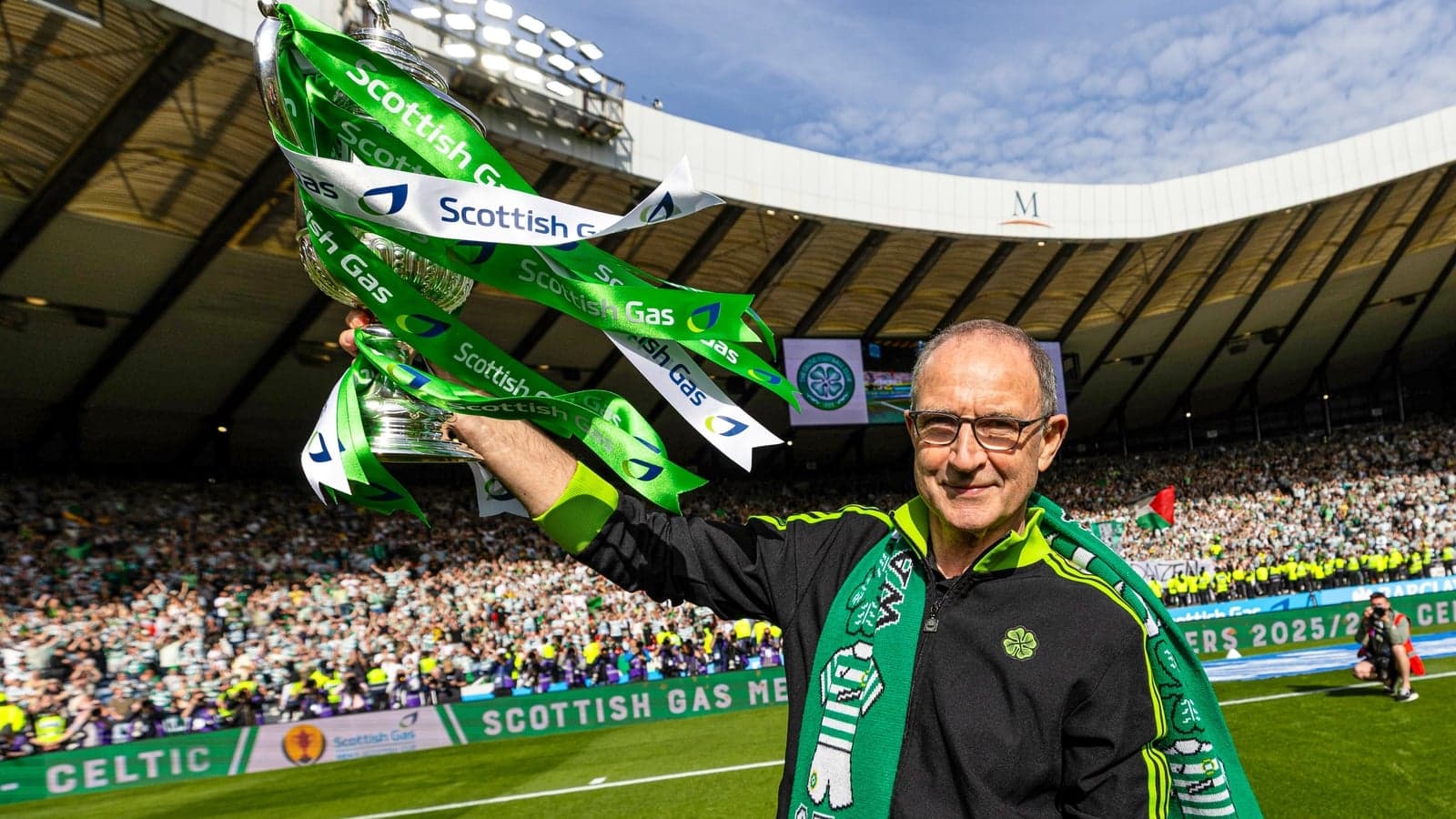Man holding trophy with Celtic colors at stadium