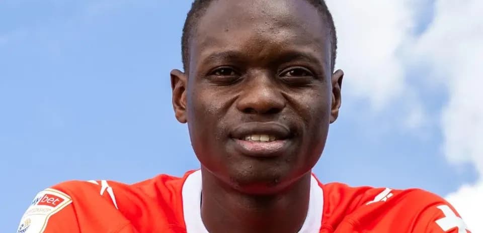 Player posing in red jersey against blue sky