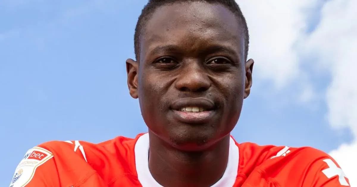 Player posing in red jersey against blue sky