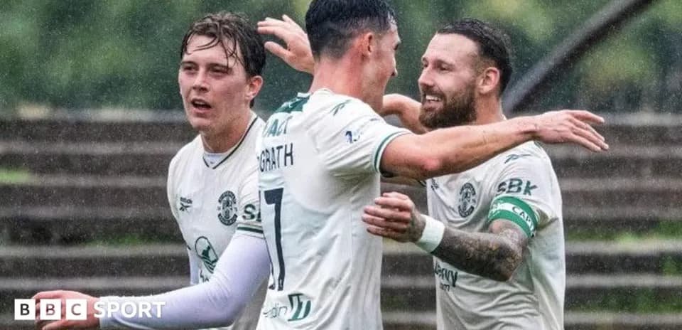 Players celebrating a goal in rainy conditions