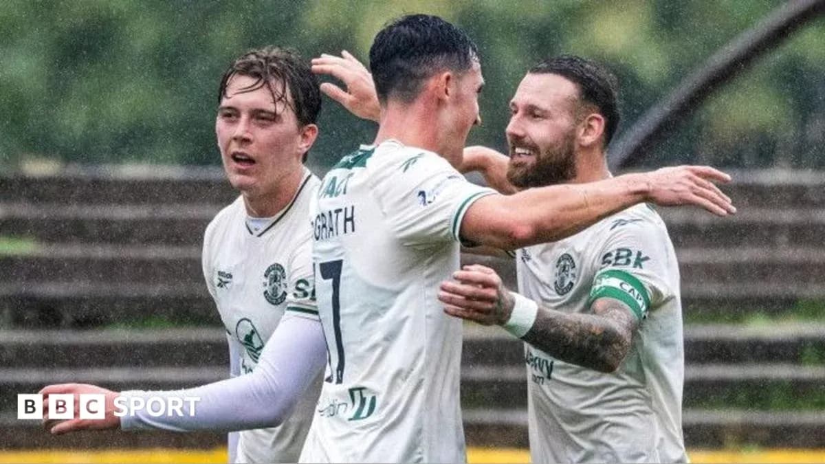 Players celebrating a goal in rainy conditions