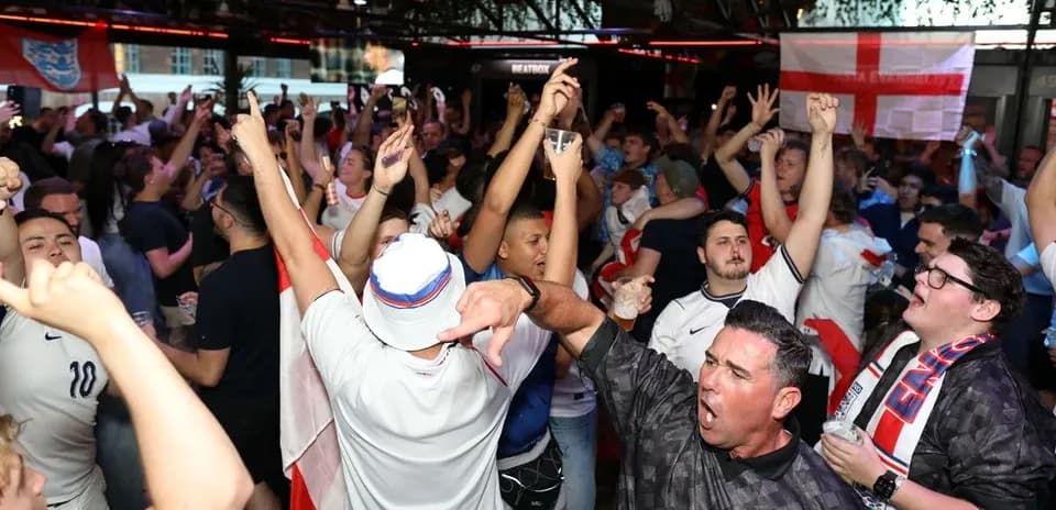 Crowd of fans celebrating in bar with drinks