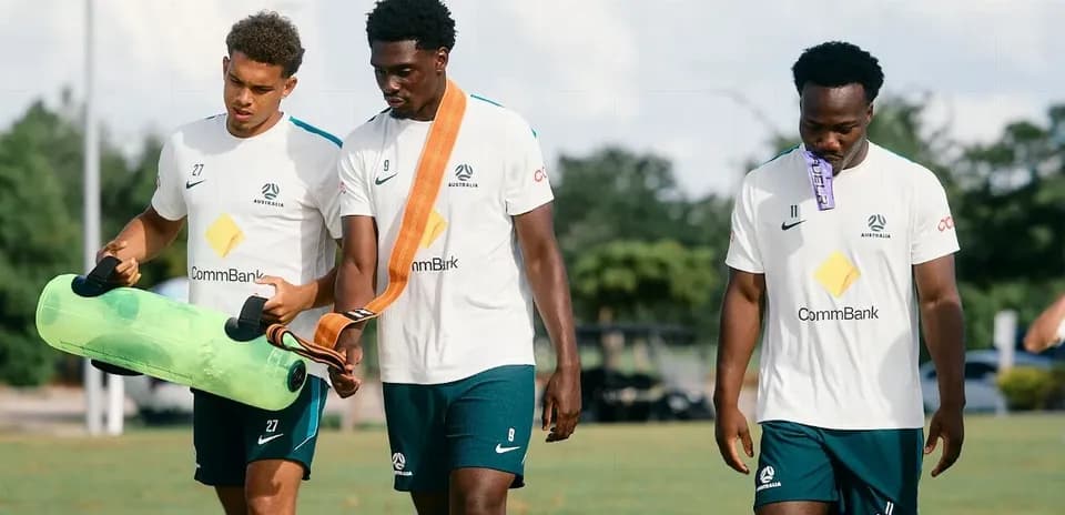 Three players walking with training equipment outdoors