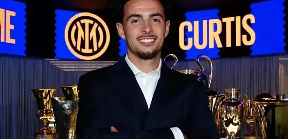 Man in suit posing in front of trophies