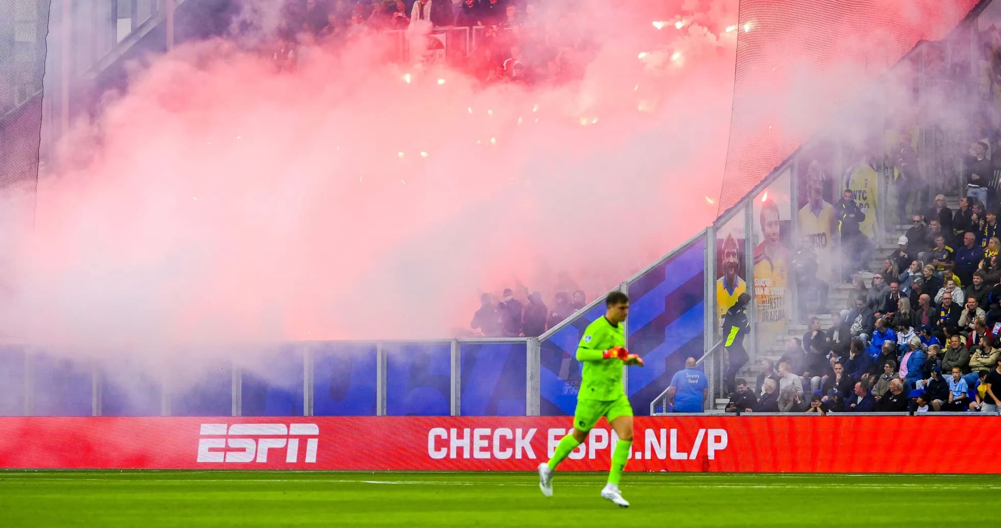 Goalkeeper walking past smoke and flares in stadium