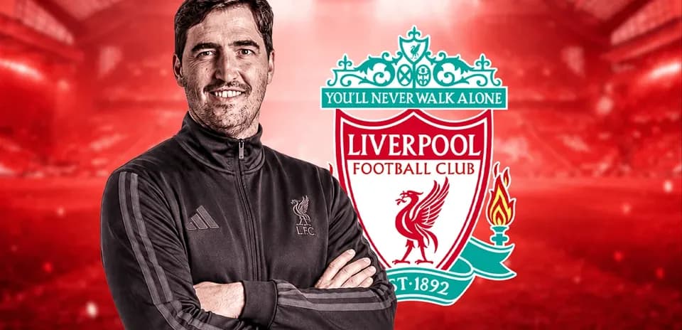 Coach posing with Liverpool FC logo in background