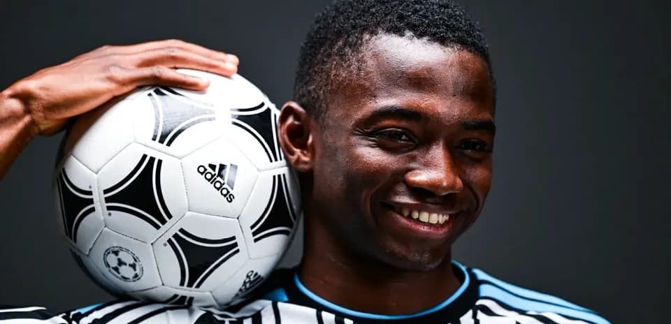 Player holding a soccer ball on his shoulder