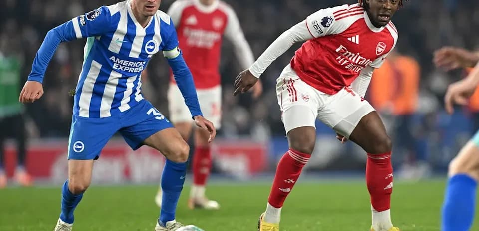 Brighton player challenging Arsenal player for the ball