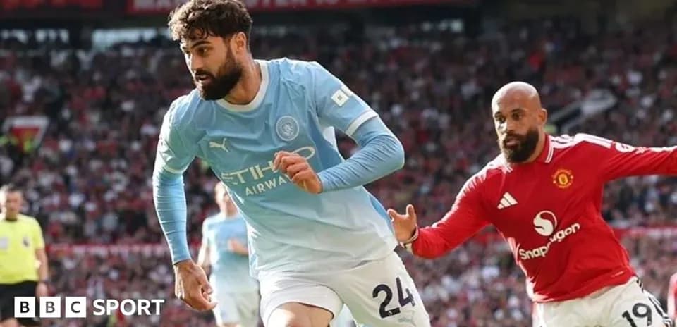 Manchester City player dribbling past Manchester United opponent