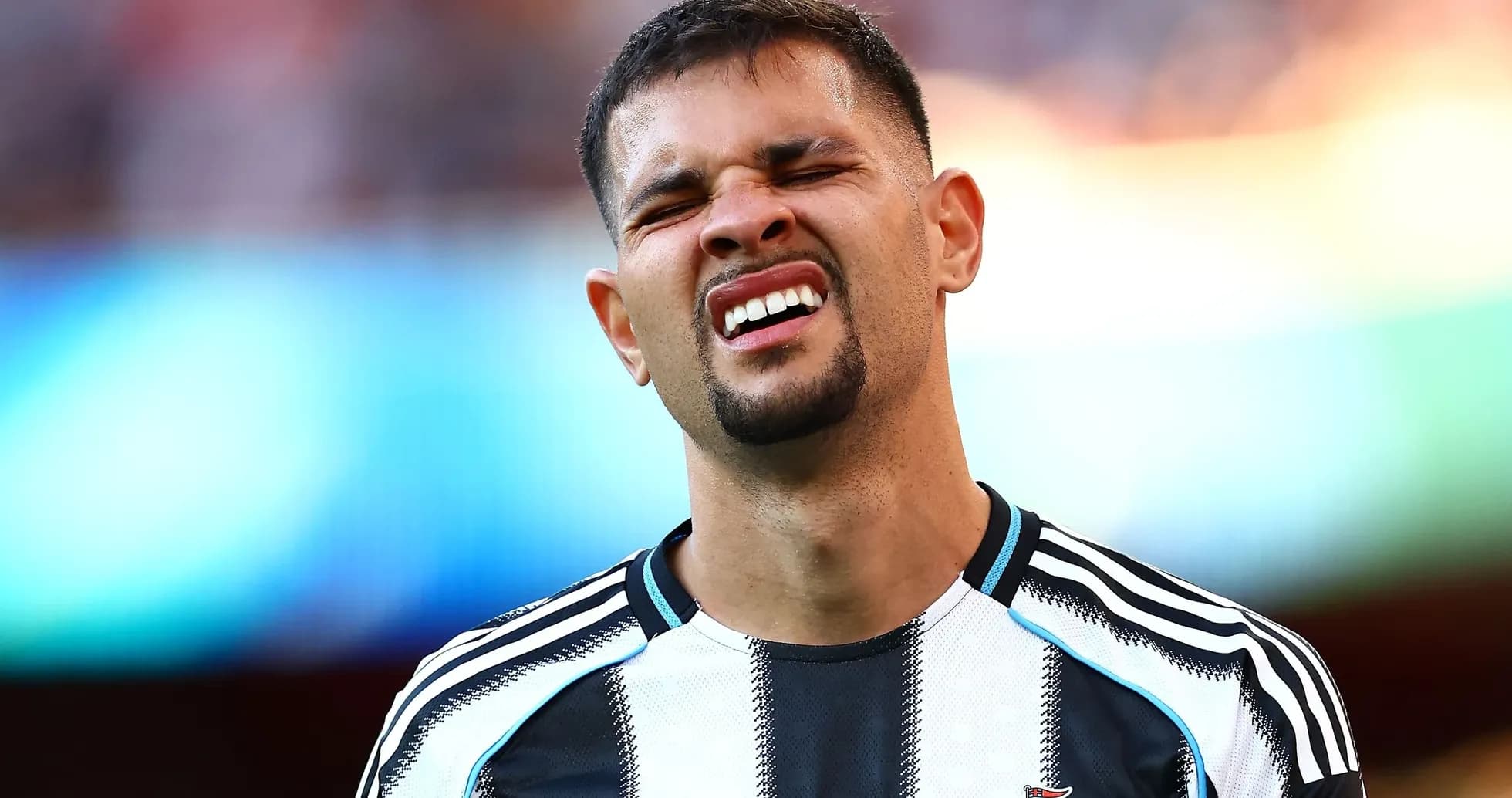 Player grimacing during match with Newcastle kit