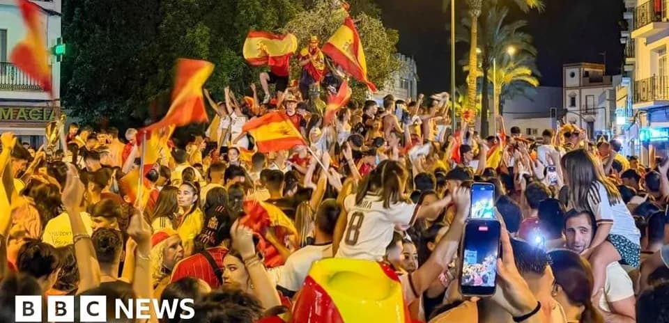Crowd celebrating with Spanish flags at night