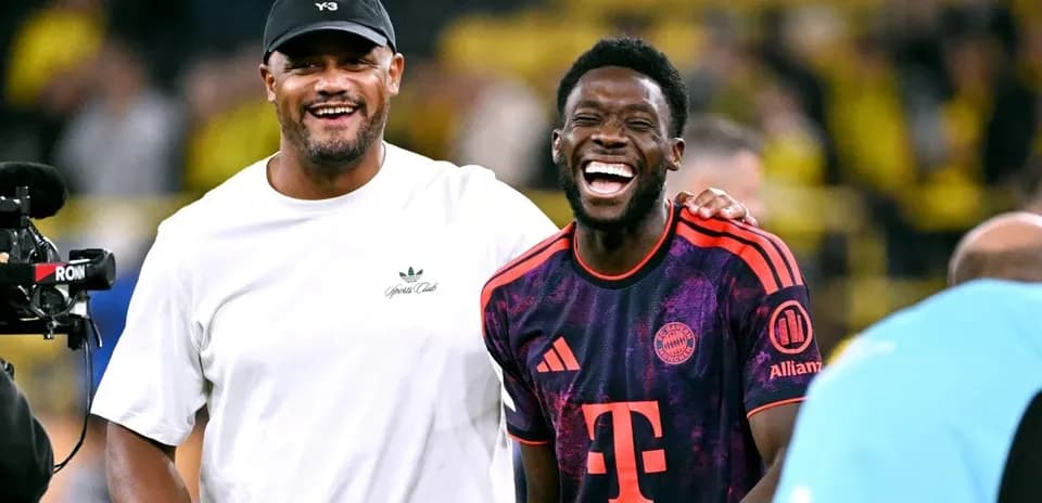 Two men laughing on the football field post-match