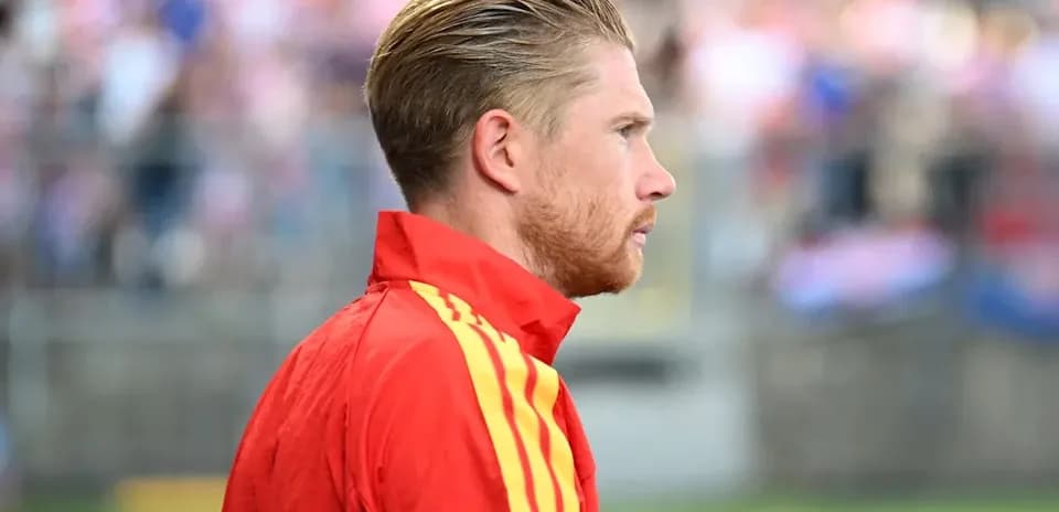 Player in red training jacket on sideline