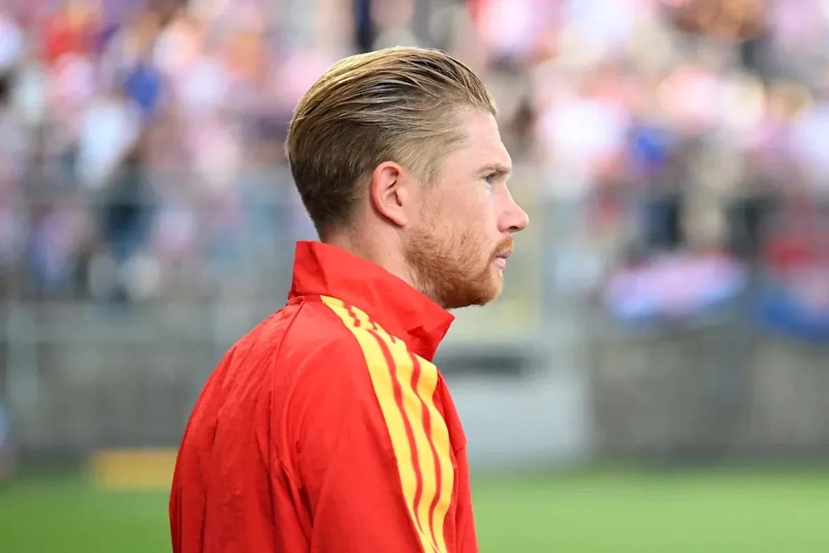 Player in red training jacket on sideline