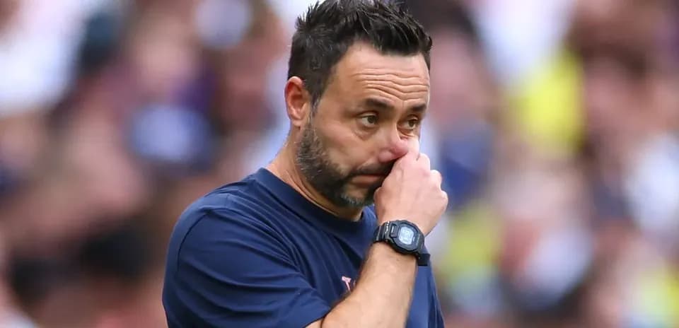 Coach observing match while touching his face