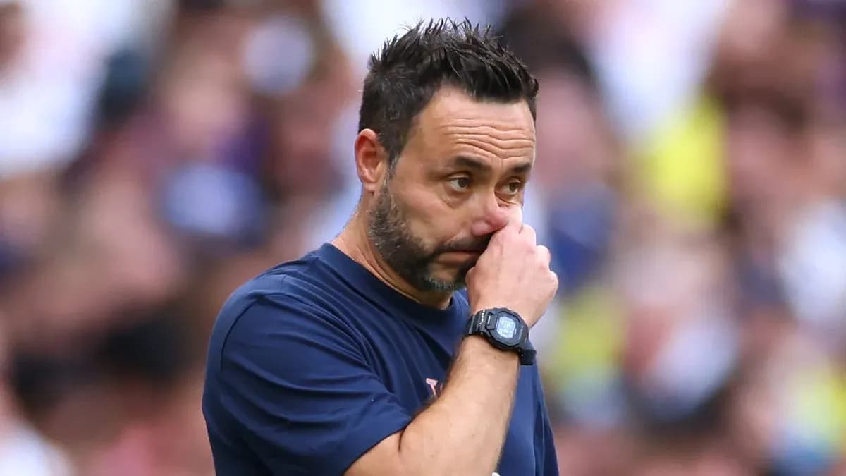 Coach observing match while touching his face