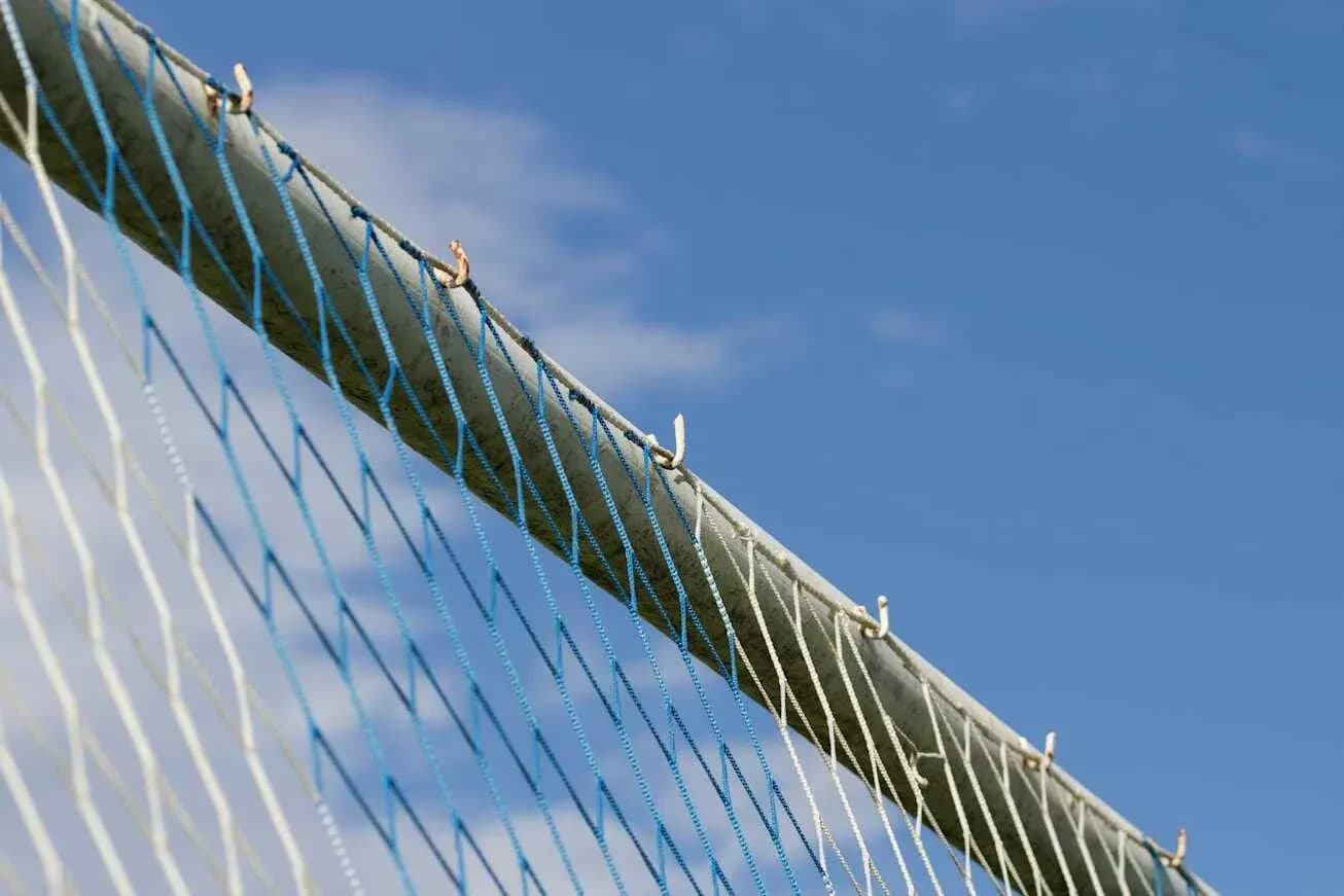 Close-up of soccer goal net against blue sky
