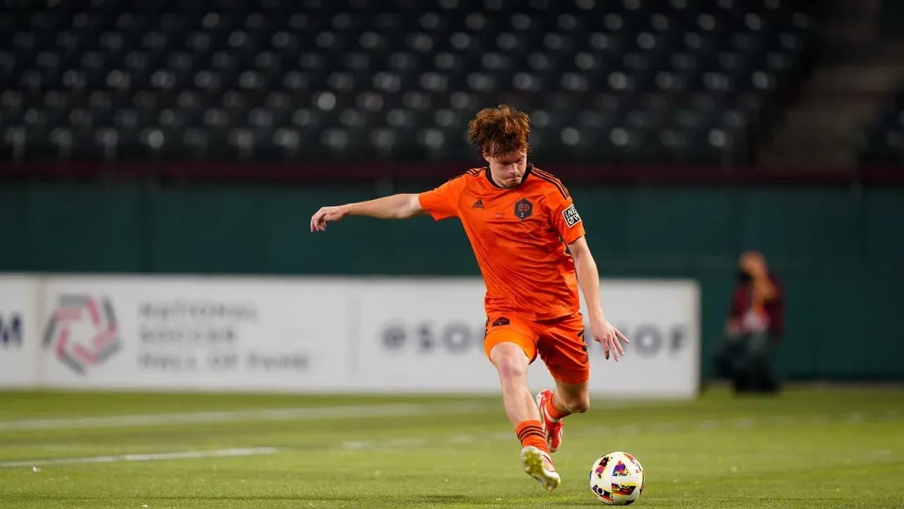 Player in orange jersey kicking soccer ball
