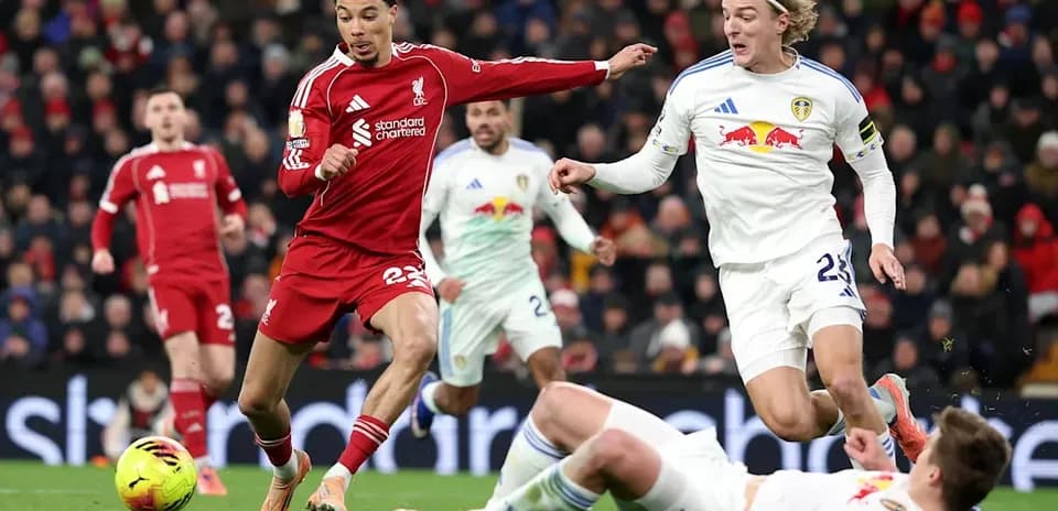 Liverpool player evading Leeds defenders during match