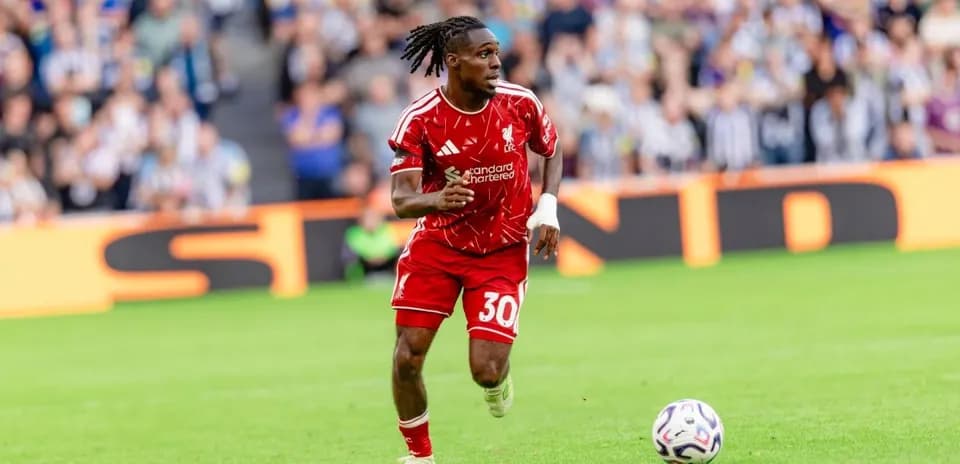 Player in red kit running with ball on field