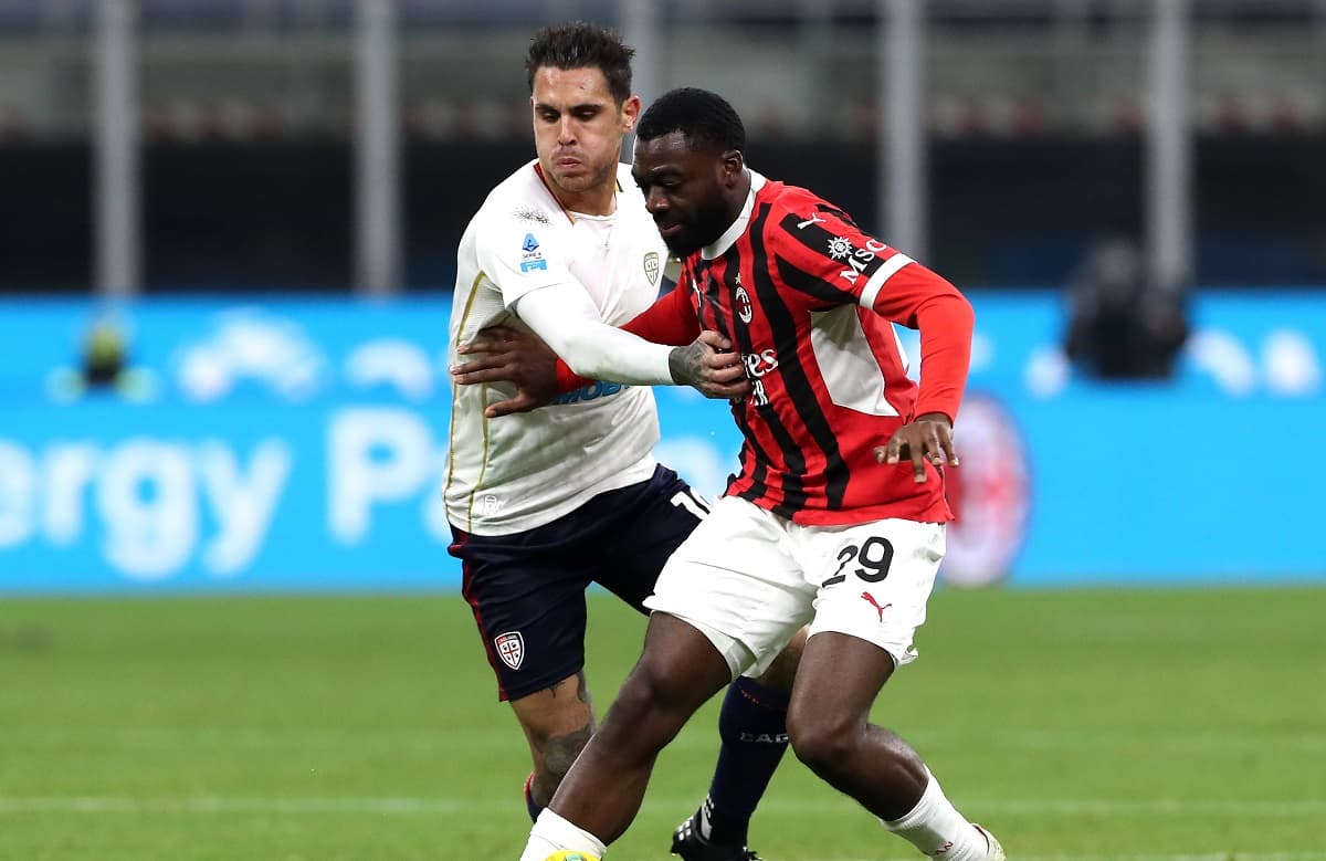 AC Milan player challenging Cagliari opponent