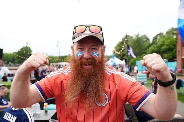 Fan celebrating with painted face and orange jersey