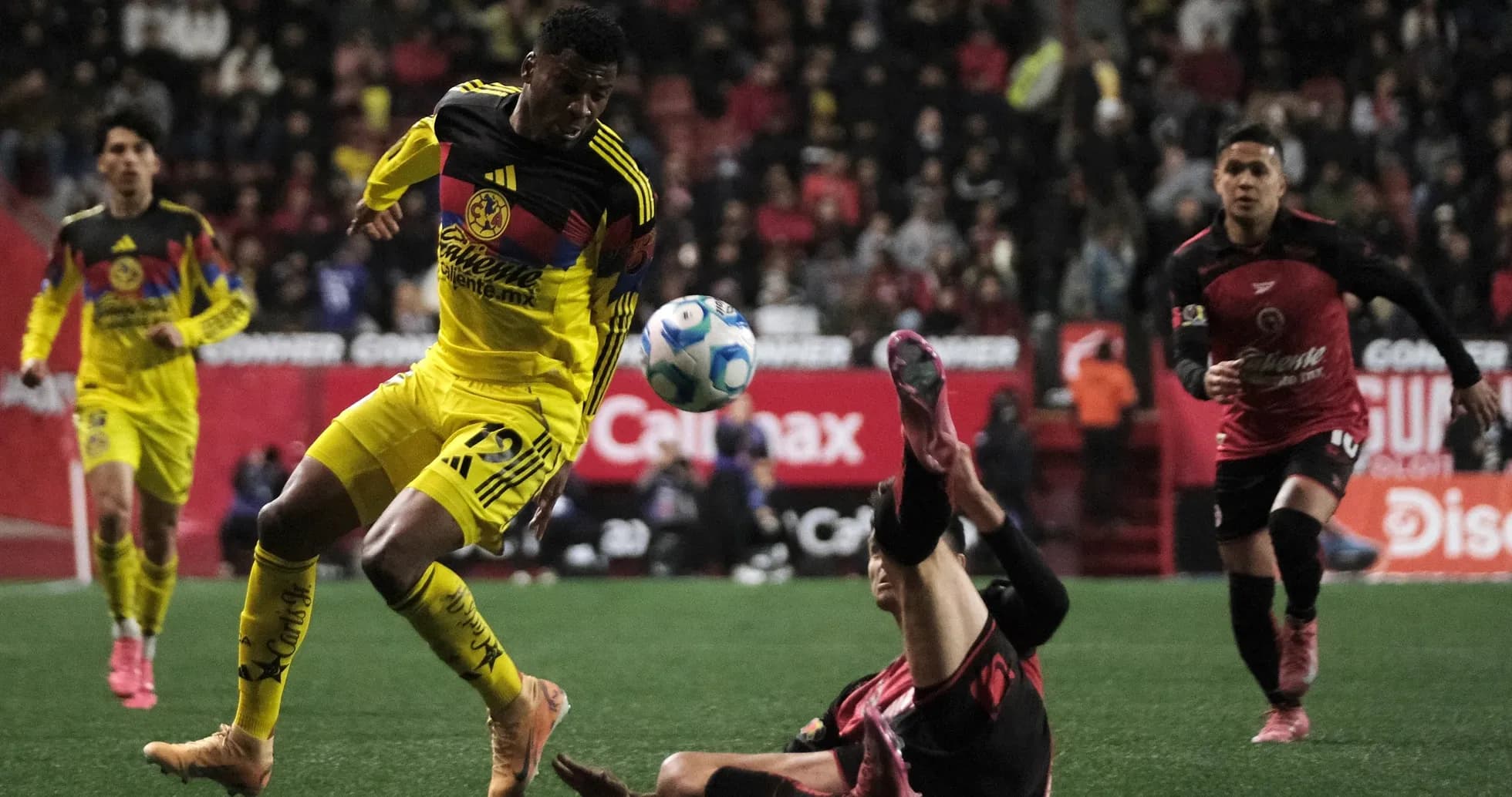 Club America player dribbling past Club Tijuana opponent
