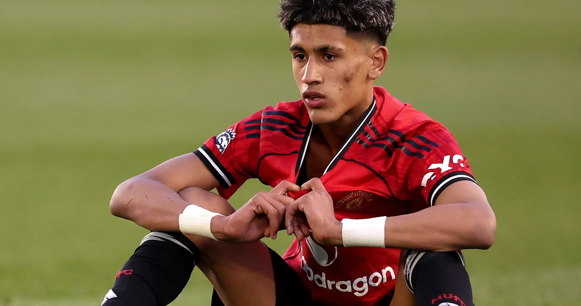 Player sitting on field in Manchester United kit
