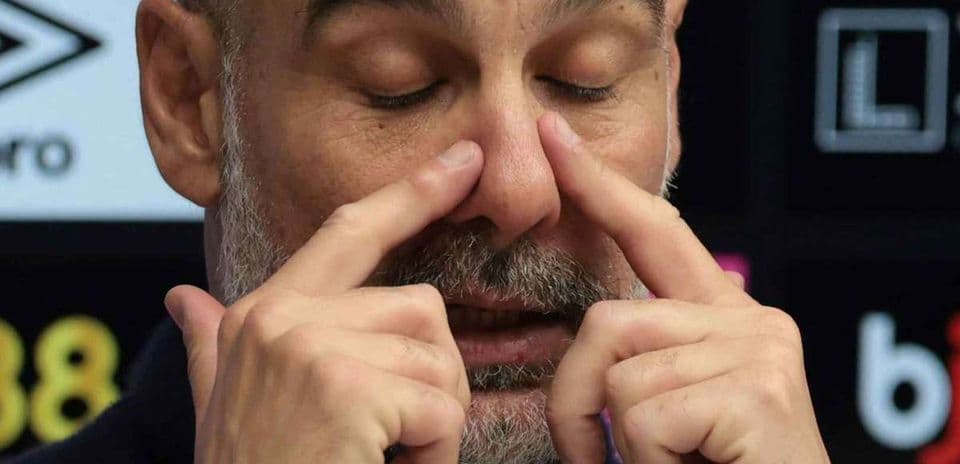 Manager gesturing during press conference with closed eyes