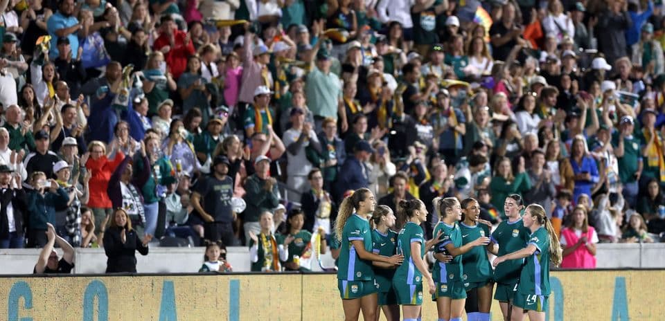 Players celebrating goal with cheering crowd