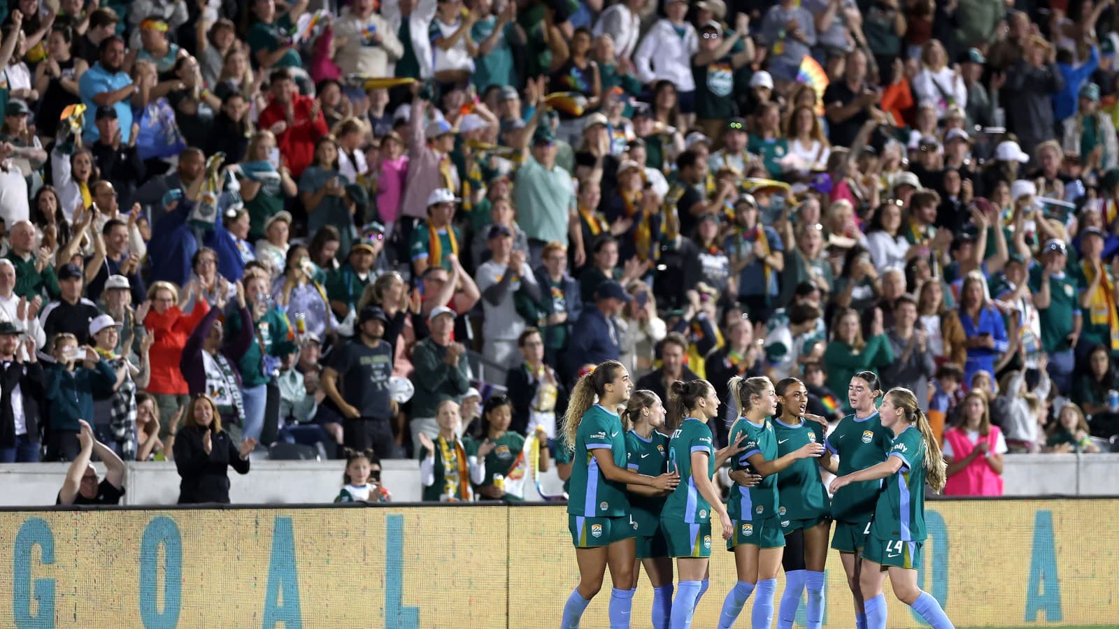 Players celebrating goal with cheering crowd