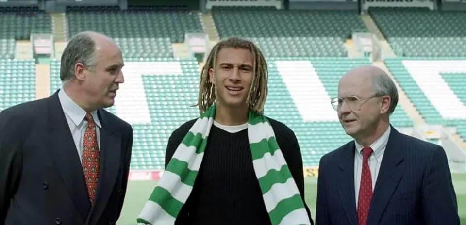 New player posing with club officials at stadium