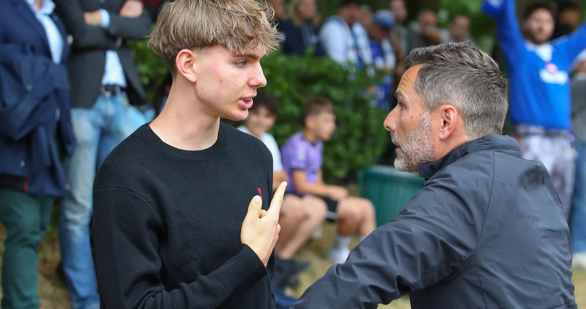 Two men discussing intensely near a sports crowd