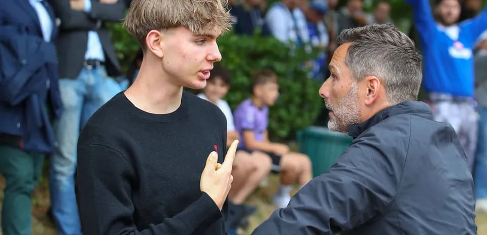 Two men discussing intensely near a sports crowd