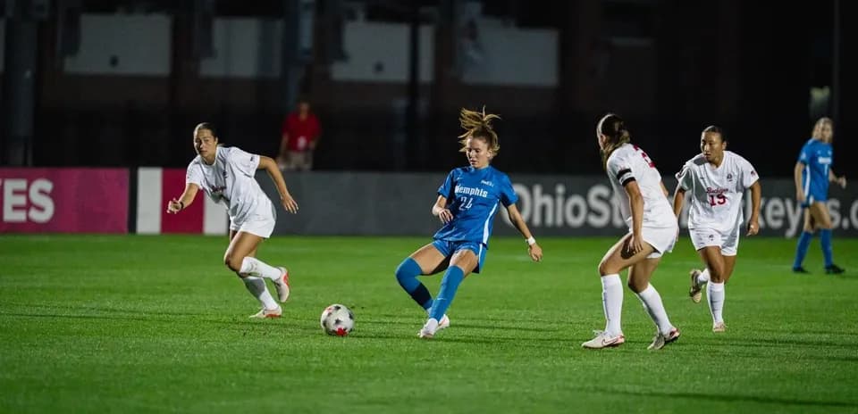 Player in blue dribbling past defenders in match