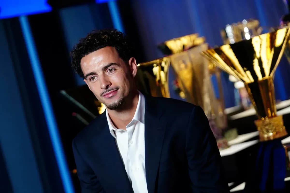 Man in suit with trophies in background