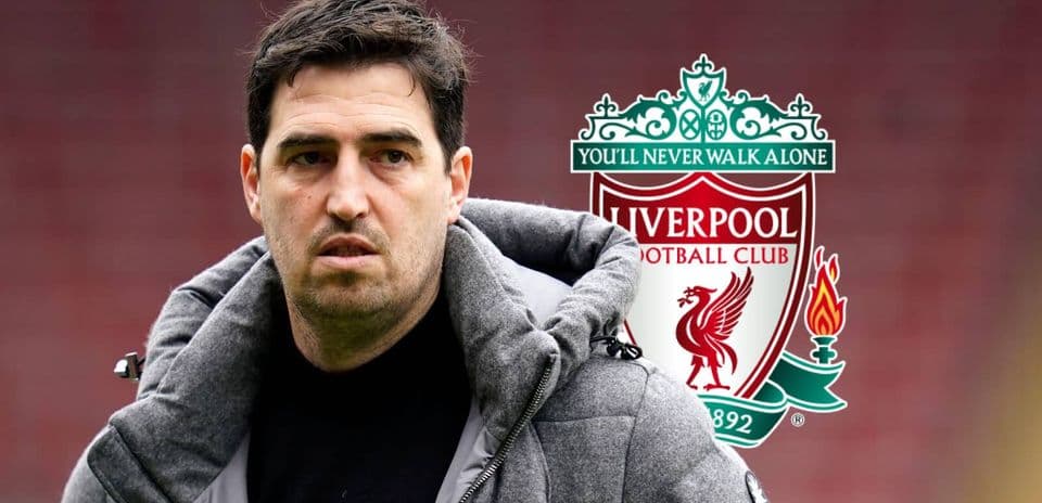 Coach standing with Liverpool FC logo in background
