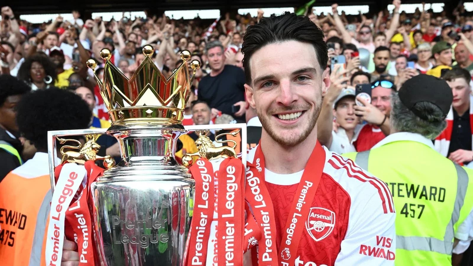 Player celebrating with Premier League trophy in crowd
