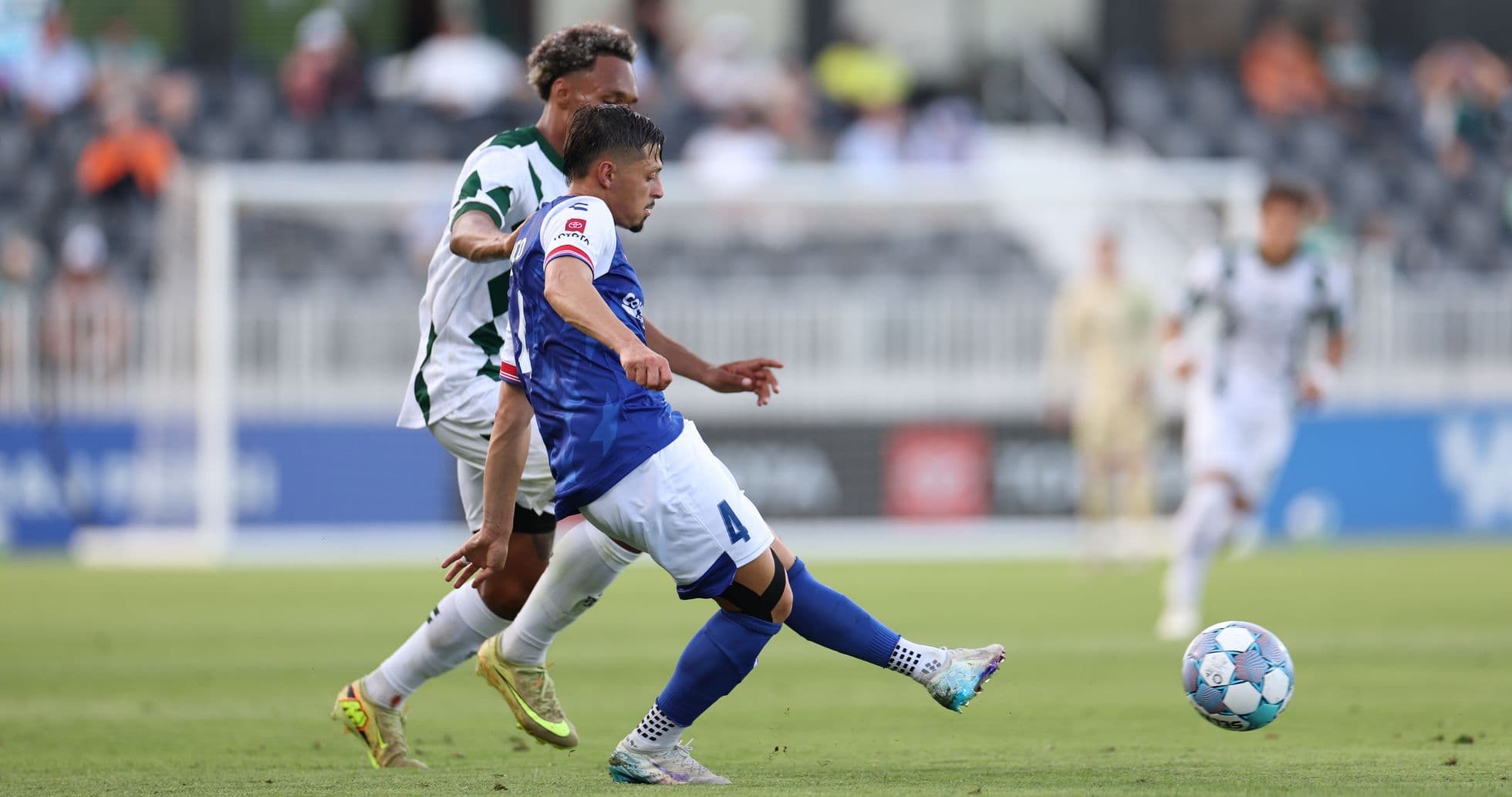 Player tackling for the ball in football match