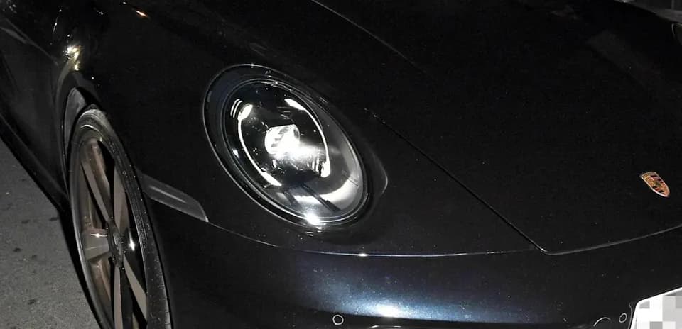 Two men in a black Porsche car at night