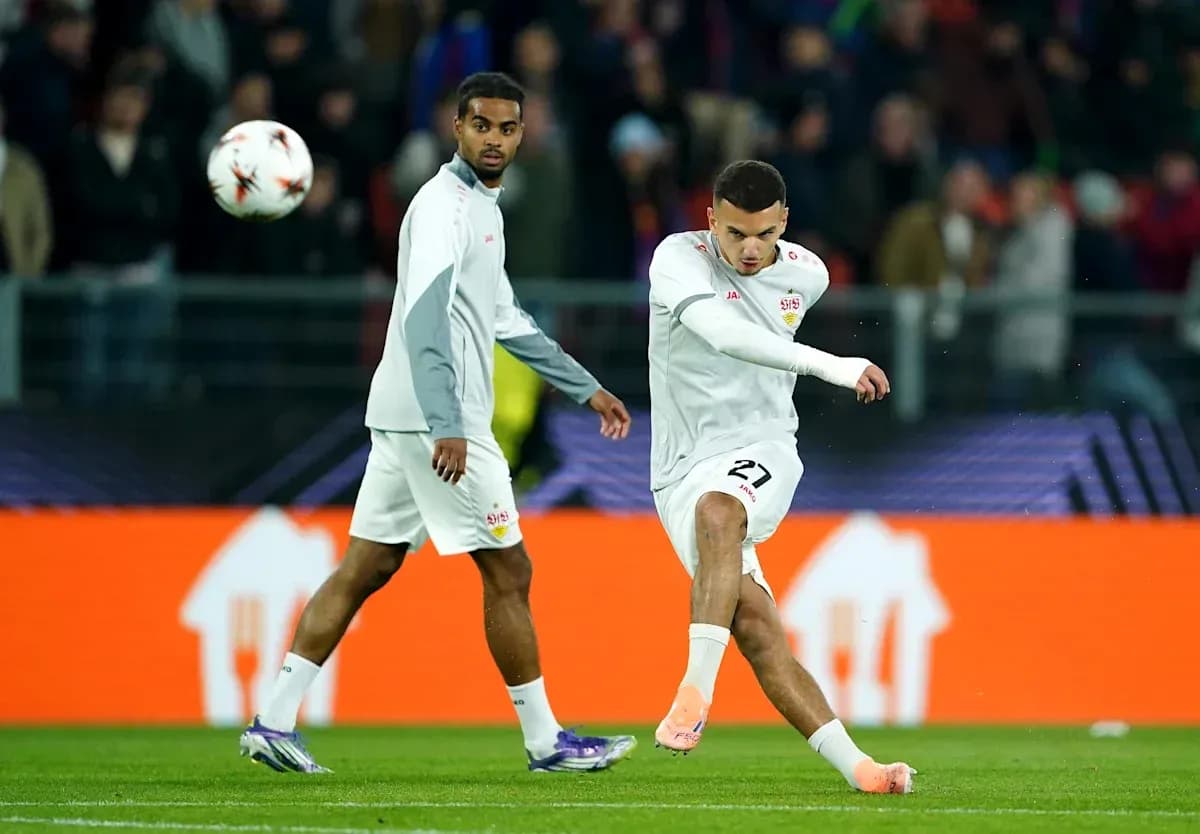 Player kicking ball while teammate observes during warm-up