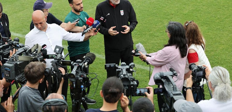 Coach speaking to media surrounded by cameras