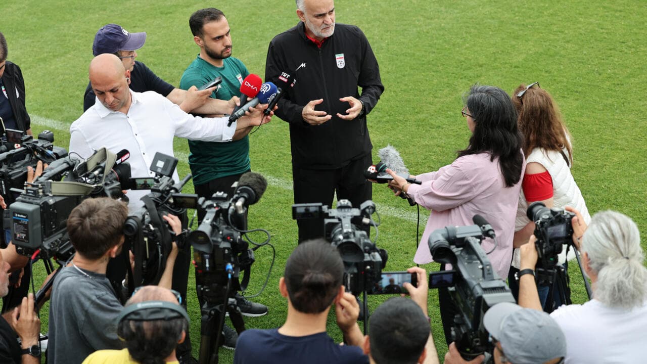 Coach speaking to media surrounded by cameras
