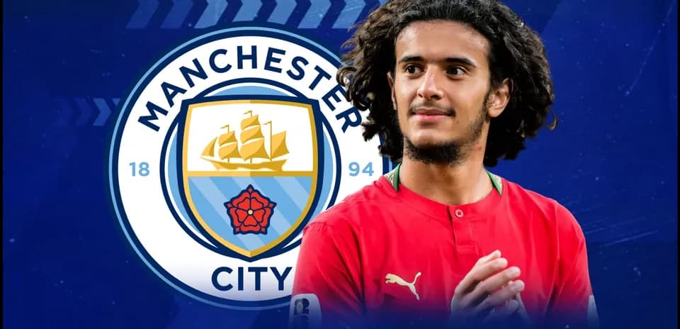 Player in red jersey with Manchester City logo backdrop
