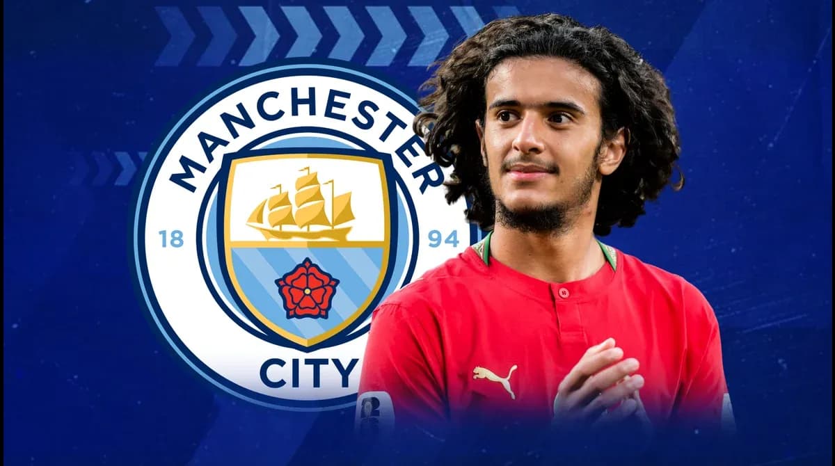 Player in red jersey with Manchester City logo backdrop