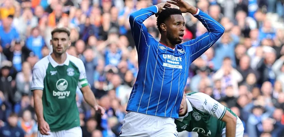 Player in blue celebrating a goal with fans in background
