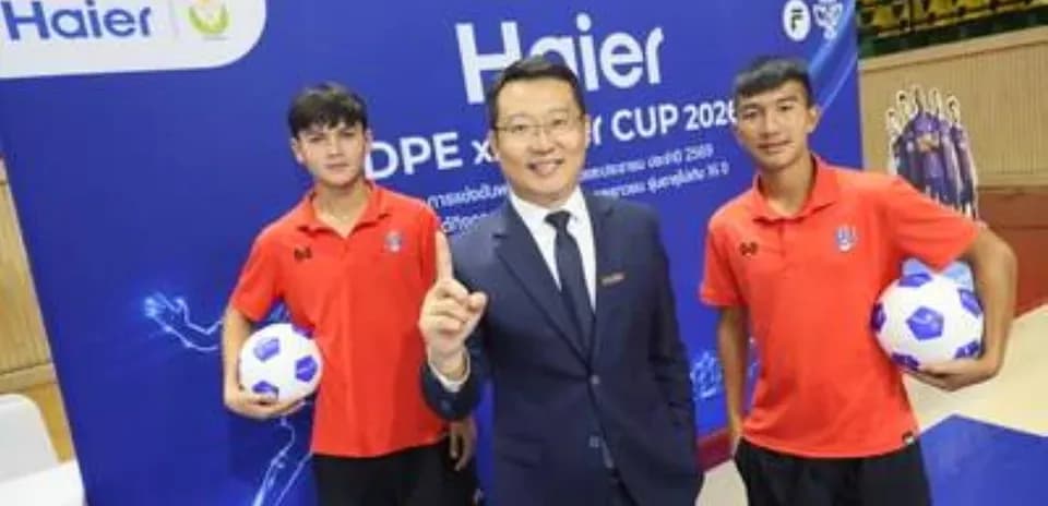 Two young football players with a businessman at event